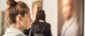 Young Woman Looking At Modern Painting In Art Gallery