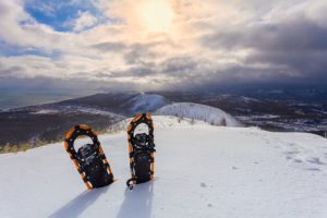 snowshoes in the snow on the winter mountains and sky with clouds background.