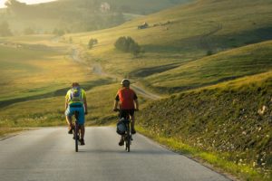 two cyclists on country road with green hills ahead