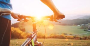 Close up of hand on bike handles looking out at a serene valley