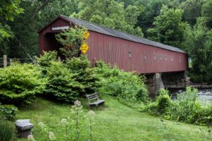 Red covered wooden bridge over river