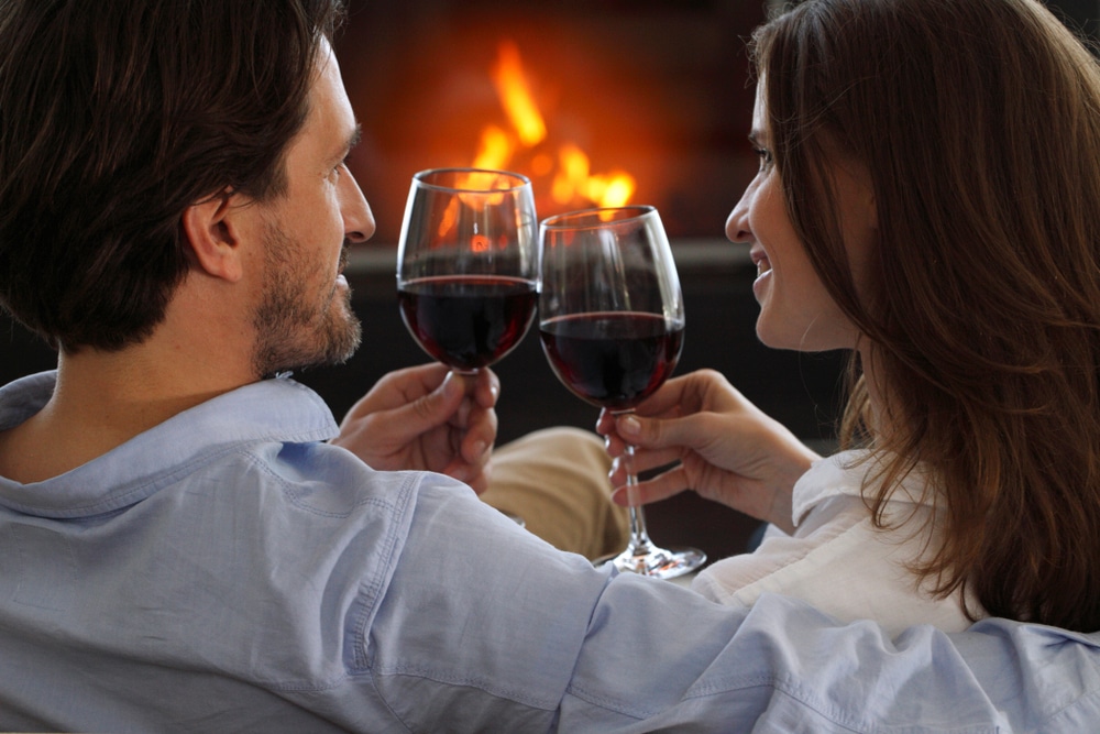 Couple drinking wine by the fire during their romantic Vermont Getaway
