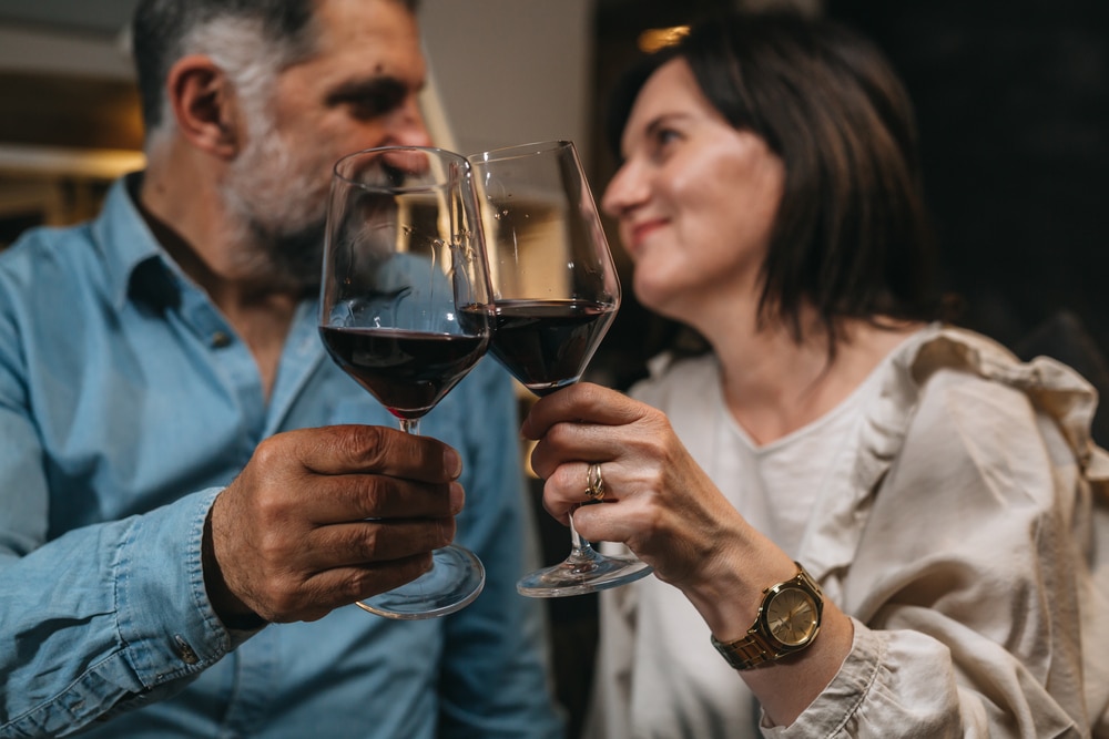 Couple toasting with a glass of red wine during their romantic Vermont Getaway