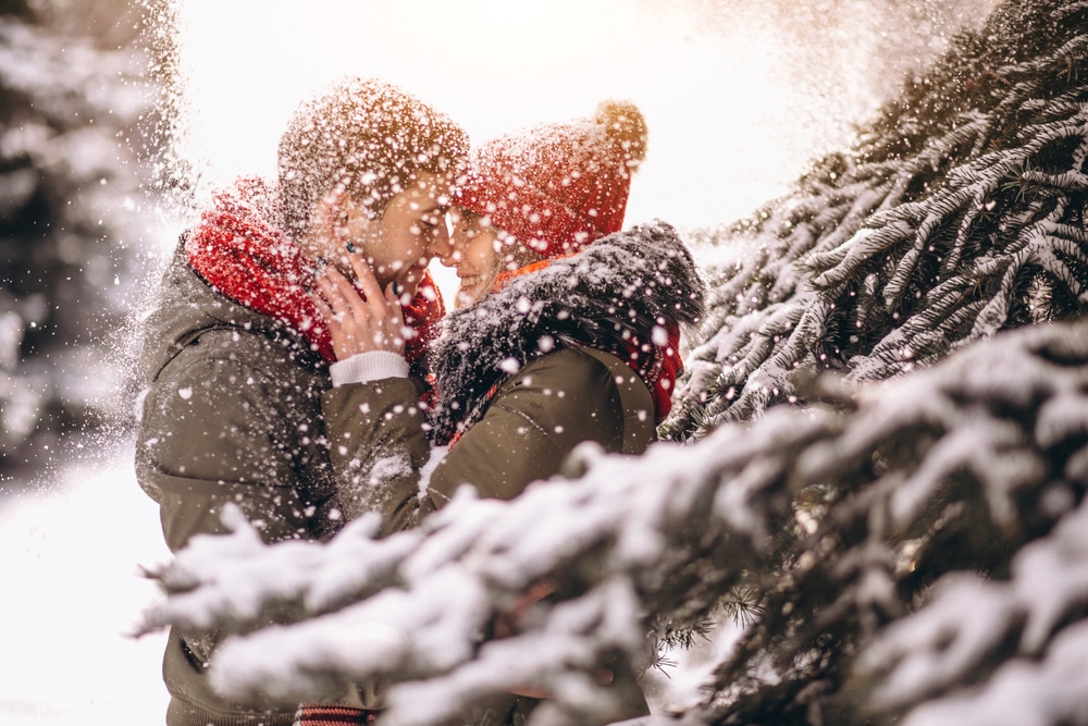 A couple sneaks a kiss in the falling snow, while enjoying romantic sleigh rides in Vermont