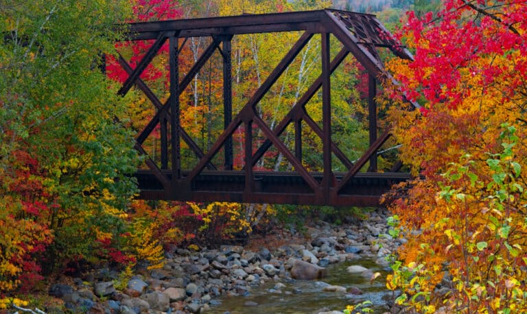 Train trestle over stream, surrounded by brilliant Vermont fall foliage near a hiking trail in Brattleboro.